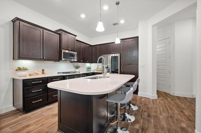 206 Olivia Dr Unit 120, Austin, TX 78738 - kitchen with a sink, wood finished floors, appliances with stainless steel finishes, light countertops, and dark brown cabinetry