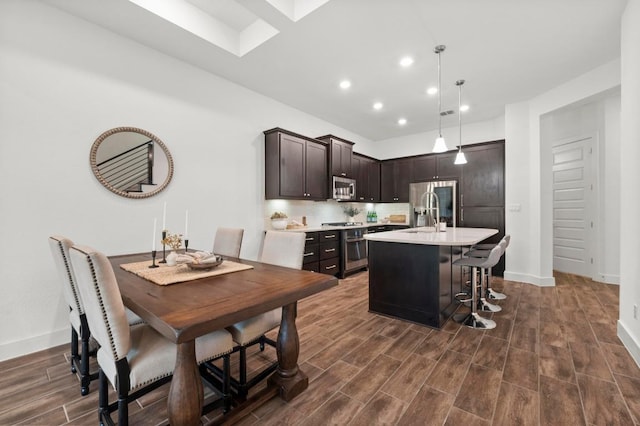 206 Olivia Dr Unit 120, Austin, TX 78738 - kitchen featuring appliances with stainless steel finishes, light countertops, dark brown cabinets, recessed lighting, and a kitchen island with sink