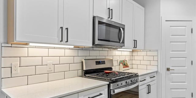 4711 Little Hill Cir, Austin, TX 78725 - kitchen featuring appliances with stainless steel finishes, tasteful backsplash, white cabinetry, light stone counters, and wood finished floors