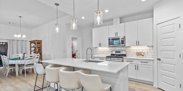 4711 Little Hill Cir, Austin, TX 78725 - kitchen with appliances with stainless steel finishes, a sink, light wood-style flooring, backsplash, and a chandelier