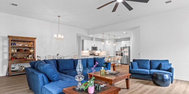 4711 Little Hill Cir, Austin, TX 78725 - living room with light wood finished floors, a ceiling fan, a chandelier, and recessed lighting