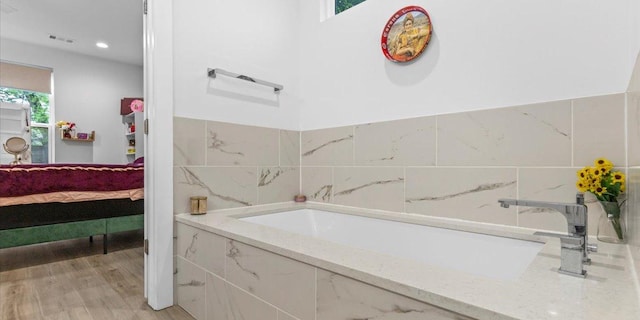 4711 Little Hill Cir, Austin, TX 78725 - bathroom featuring connected bathroom, a bath, wood finished floors, recessed lighting, and tile walls