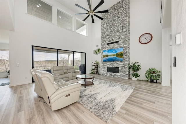 2420 Novara Trl, Leander, TX 78641 - living room featuring a towering ceiling, ceiling fan, a fireplace, and wood finished floors