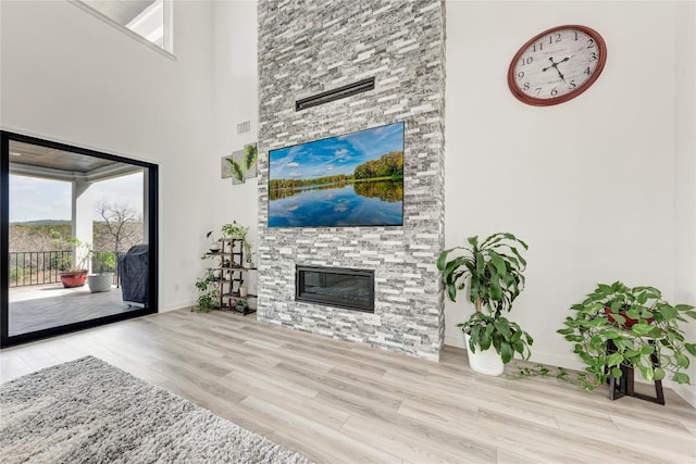 2420 Novara Trl, Leander, TX 78641 - living area with wood finished floors, a towering ceiling, healthy amount of natural light, and a stone fireplace