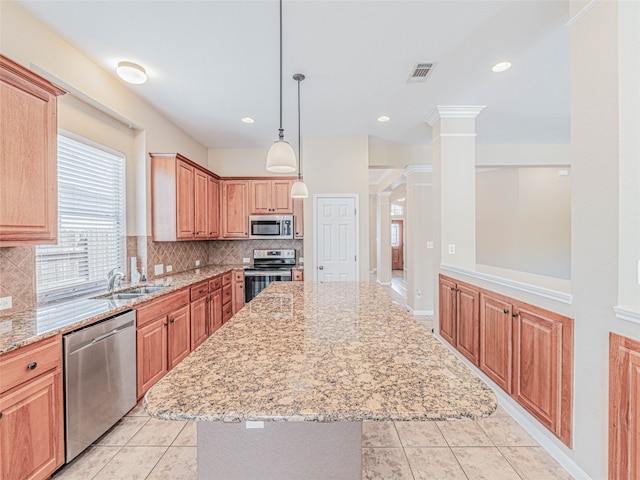 2009 Tillman Dr, Cedar Park, TX 78613 - kitchen featuring decorative columns, appliances with stainless steel finishes, a center island, light stone counters, and light tile patterned floors