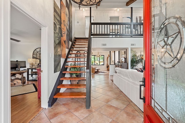 foyer with a chandelier, stairs, ornamental molding, and light tile patterned flooring