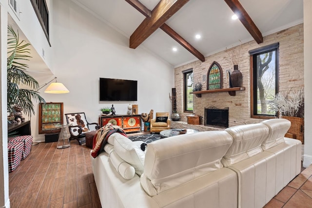 living area featuring beamed ceiling, a stone fireplace, high vaulted ceiling, and wood finished floors