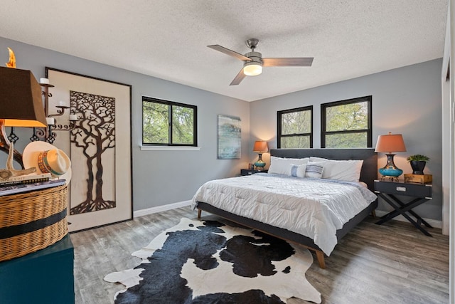bedroom with baseboards, a ceiling fan, wood finished floors, and a textured ceiling