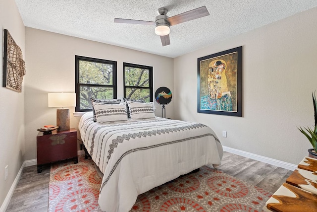 bedroom featuring a textured ceiling, wood finished floors, and baseboards