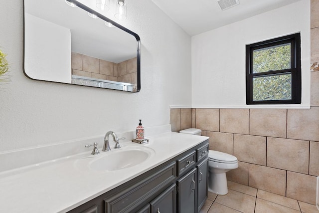 full bathroom featuring vanity, tile patterned floors, toilet, visible vents, and tile walls