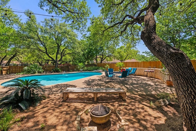 view of swimming pool with a fenced in pool, a diving board, a fire pit, a patio area, and a fenced backyard