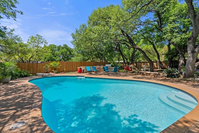 view of swimming pool with a diving board, a patio area, a fenced backyard, outdoor dining space, and a fenced in pool