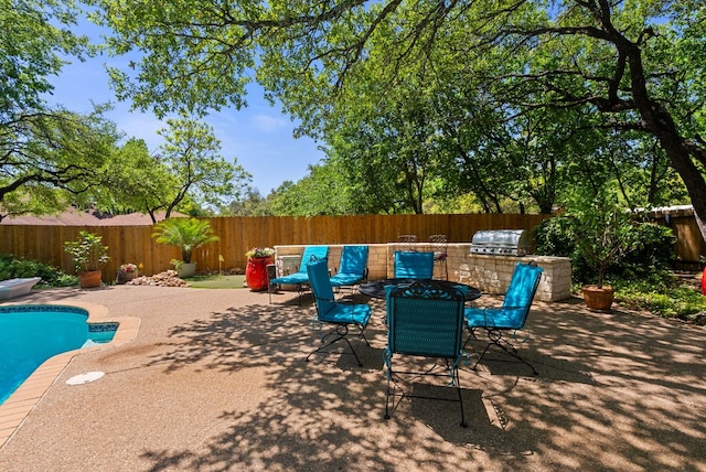 view of patio / terrace featuring a grill, a fenced backyard, a fenced in pool, and exterior kitchen