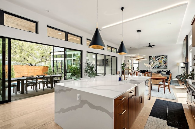 2116 Kenwood Ave, Austin, TX 78704 - kitchen featuring modern cabinets, light wood-style flooring, a spacious island, open floor plan, and pendant lighting
