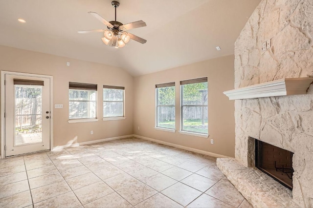 unfurnished living room with a ceiling fan, light tile patterned floors, a stone fireplace, and vaulted ceiling