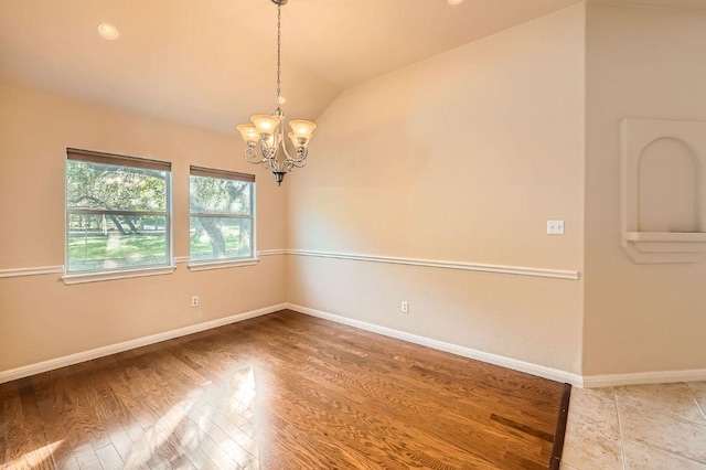 spare room with baseboards, vaulted ceiling, wood finished floors, and an inviting chandelier