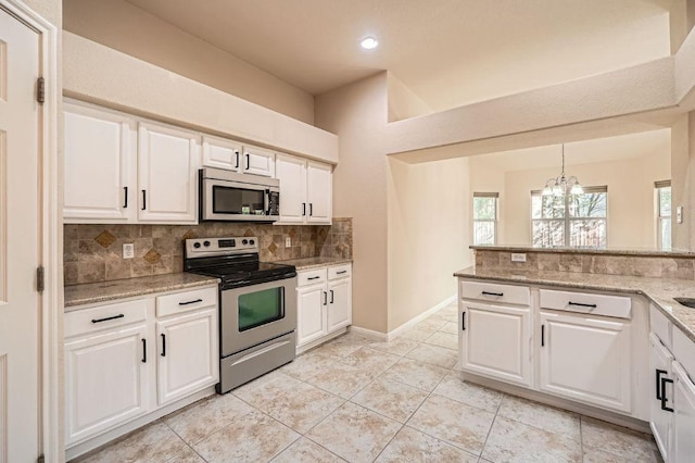 kitchen featuring tasteful backsplash, a chandelier, white cabinets, light stone countertops, and appliances with stainless steel finishes