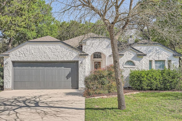 view of front of house featuring stone siding, a front yard, driveway, and an attached garage