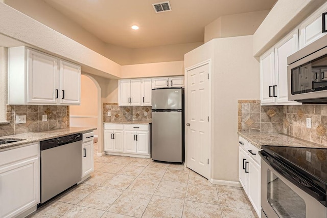 kitchen featuring white cabinets, tasteful backsplash, appliances with stainless steel finishes, and visible vents
