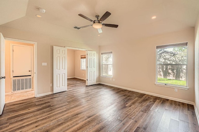 empty room with visible vents, a wealth of natural light, wood finished floors, and a ceiling fan