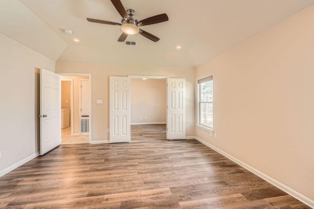 unfurnished bedroom featuring baseboards, lofted ceiling, visible vents, and wood finished floors