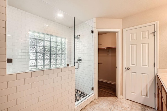bathroom with recessed lighting, tile patterned floors, a spacious closet, and a shower stall