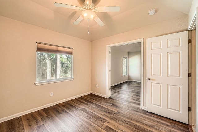 unfurnished room with plenty of natural light, ceiling fan, and dark wood finished floors