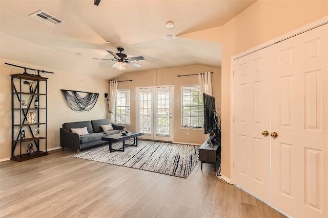 living room featuring ceiling fan, visible vents, vaulted ceiling, baseboards, and light wood-style floors