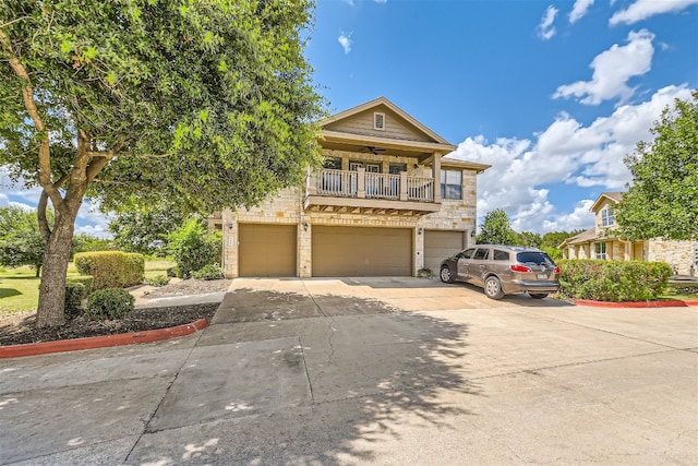 9201 Brodie Ln Unit 201, Austin, TX 78748 - view of front of home featuring an attached garage, driveway, stone siding, a balcony, and a ceiling fan