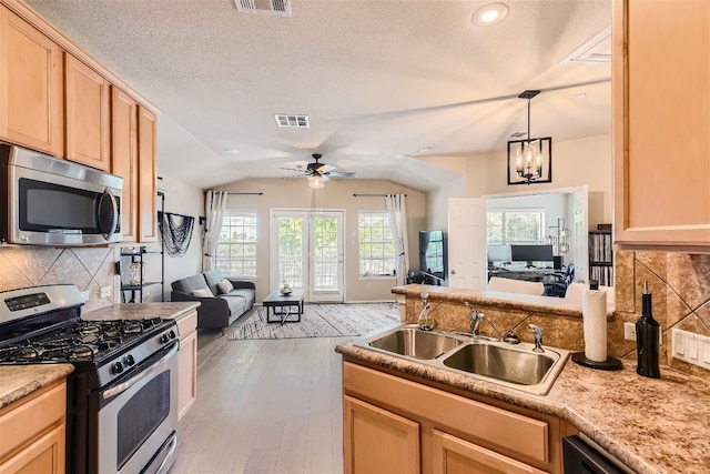 kitchen with light brown cabinetry, appliances with stainless steel finishes, a sink, open floor plan, and visible vents