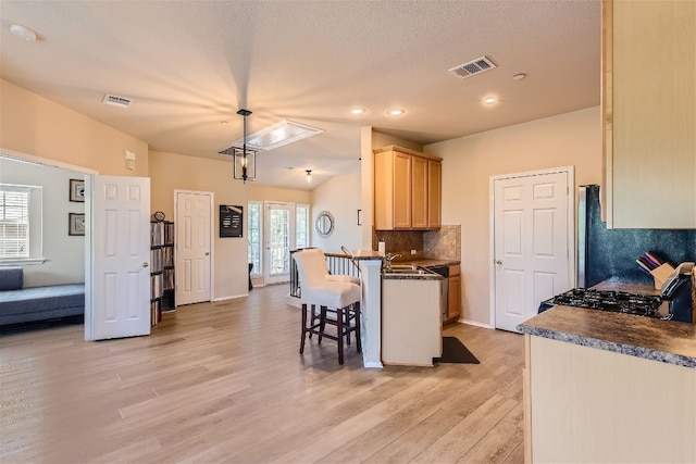 kitchen with range with gas cooktop, dark countertops, visible vents, and light wood-style floors
