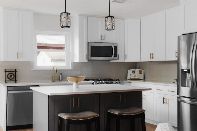 6307 Cannonleague Dr, Austin, TX 78745 - kitchen with appliances with stainless steel finishes, a center island, light countertops, a kitchen breakfast bar, and decorative backsplash