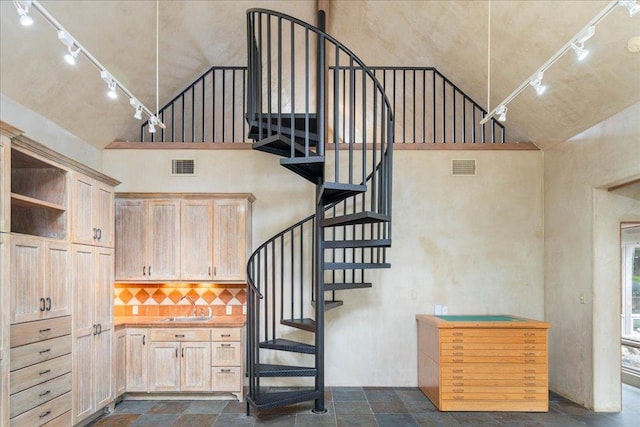stairway featuring stone tile floors, high vaulted ceiling, rail lighting, and visible vents