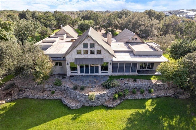 24736 Travis Lakeside Cv, Spicewood, TX 78669 - back of property featuring a lawn, a chimney, stone siding, and a wooded view