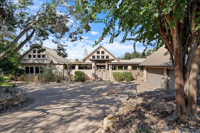 24736 Travis Lakeside Cv, Spicewood, TX 78669 - view of front facade featuring driveway, an attached garage, a gate, a chimney, and metal roof