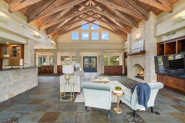 living area with visible vents, wooden ceiling, beam ceiling, and stone tile floors