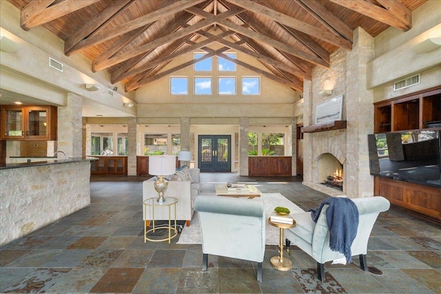 24736 Travis Lakeside Cv, Spicewood, TX 78669 - living area with wood ceiling with exposed beams, high vaulted ceiling, stone tile floors, and a stone fireplace