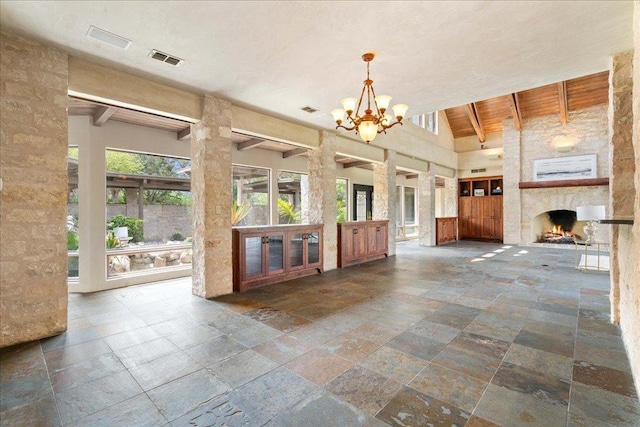unfurnished living room featuring stone tile floors, beamed ceiling, and a towering ceiling