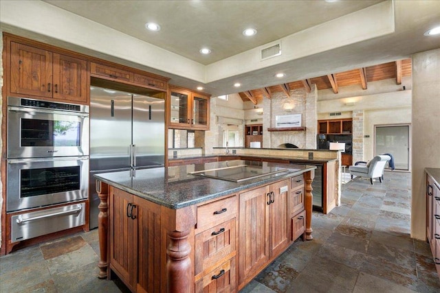 kitchen featuring visible vents, a center island, appliances with stainless steel finishes, a warming drawer, and stone tile floors