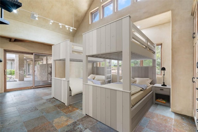 bedroom with high vaulted ceiling, access to exterior, and stone tile flooring