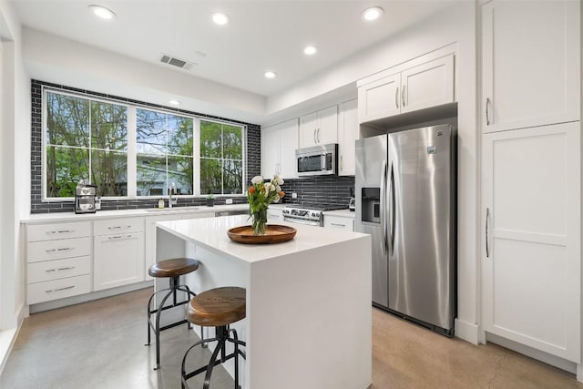 1503 Richcreek Rd Unit A, Austin, TX 78757 - kitchen with appliances with stainless steel finishes, concrete flooring, tasteful backsplash, a breakfast bar, and recessed lighting