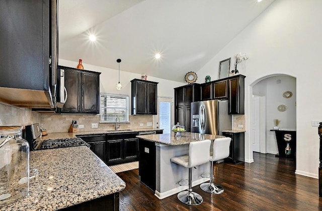 2605 Etta May Ln, Leander, TX 78641 - kitchen with appliances with stainless steel finishes, arched walkways, a sink, light stone countertops, and high vaulted ceiling