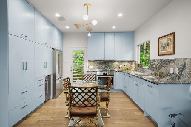 2007 Alameda Dr, Austin, TX 78704 - kitchen with appliances with stainless steel finishes, dark stone counters, backsplash, light wood finished floors, and recessed lighting
