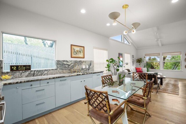2007 Alameda Dr, Austin, TX 78704 - kitchen with light wood-style flooring, white dishwasher, backsplash, vaulted ceiling, and light stone counters