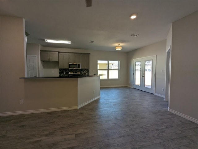 407 Gamel St, Lampasas, TX 76550 - kitchen with appliances with stainless steel finishes, backsplash, dark wood-type flooring, dark countertops, and french doors