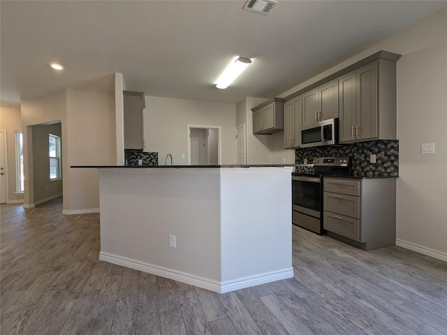 407 Gamel St, Lampasas, TX 76550 - kitchen featuring stainless steel appliances, gray cabinetry, dark countertops, decorative backsplash, and baseboards