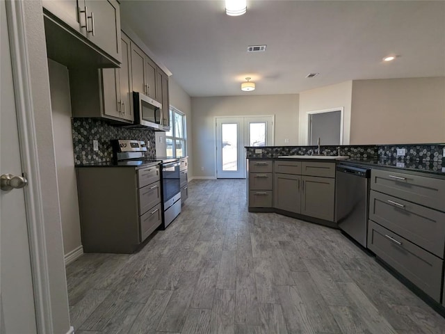 407 Gamel St, Lampasas, TX 76550 - kitchen with appliances with stainless steel finishes, gray cabinets, dark countertops, and backsplash