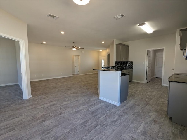 407 Gamel St, Lampasas, TX 76550 - kitchen with dark countertops, ceiling fan, wood finished floors, recessed lighting, and a peninsula