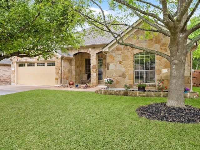 single story home featuring stone siding, a garage, a front yard, roof with shingles, and driveway