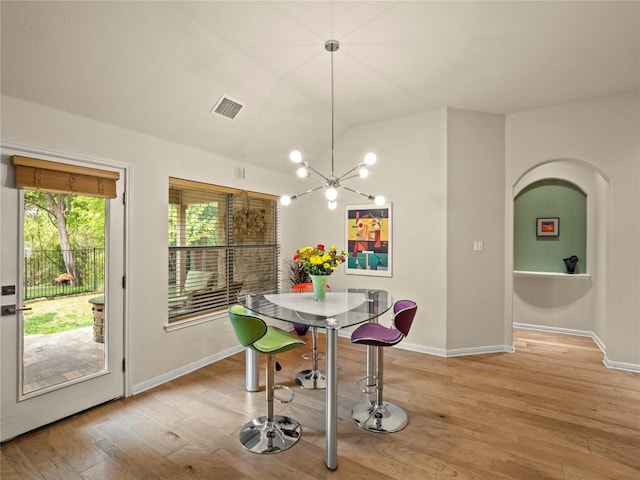 dining room with an inviting chandelier, light wood-style floors, lofted ceiling, and visible vents